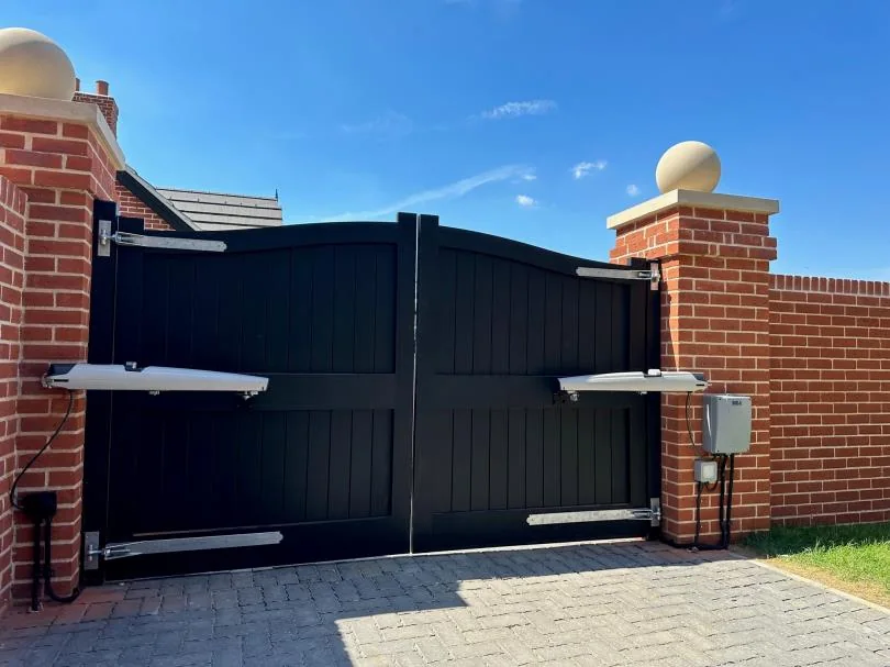 A pair of black driveway gates with automation arms