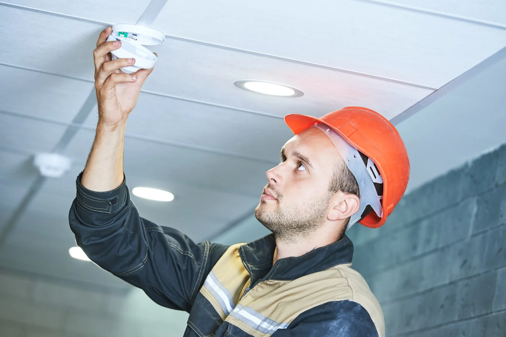 Engineer working on a ceiling-mounted fire detection device